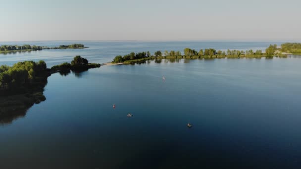 Aero, beautiful summer sunset landscape over the river. people sail on SUPs, paddle boards on water of large river. SUP training - awesome active recreation in nature. — Stock Video