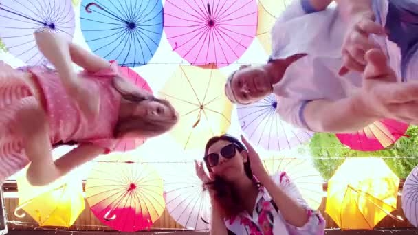 Famiglia di tre, mamma, papà e figlia, farsi selfie, sullo sfondo di appendere ombrelli decorativi multicolori. ballano e si divertono durante le riprese video. — Video Stock