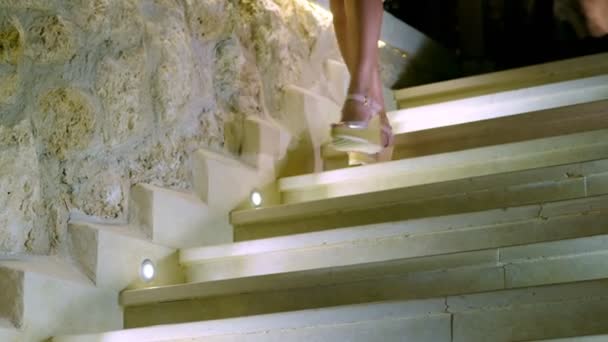 Közelkép, gyönyörű női hosszú lábak szandálban, lefelé menet a márványon, fehér lépések háttérvilágítással — Stock videók