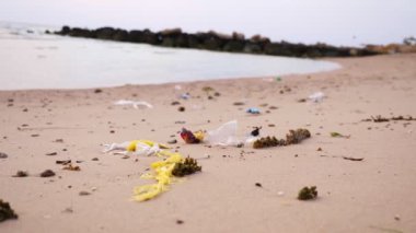 Yakın plan. Çöp, sahildeki çöp. Bir sürü plastik torba, kullanılmış plastik bardaklar ve koruyucu maskeler. Çevre kirliliği kavramı.