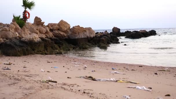 Närbild. Skräp, skräp på stranden. en hel del plastpåsar, använda plastkoppar och skyddsmasker. Miljöföroreningskoncept. — Stockvideo