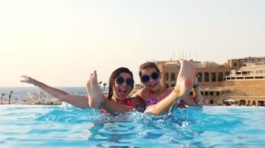 Kadın ve genç kız, anne ve kız, komik, tıpatıp aynı, yuvarlak güneş gözlükleriyle, rahatlayın, lüks otel manzaralı açık havuzda eğlenin. Aile tatili kavramı