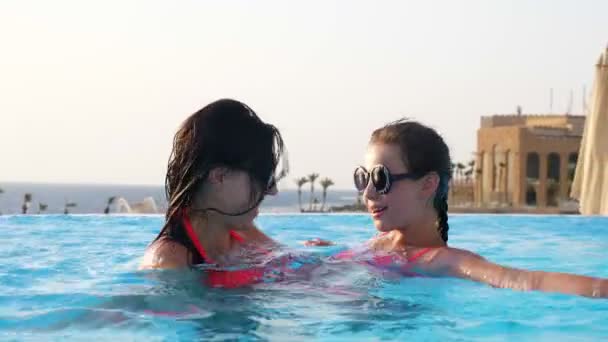 Donna e teen girl, mamma e figlia, in divertenti, identici, occhiali da sole rotondi, rilassarsi, divertirsi in piscina all'aperto con vista hotel di lusso. concetto di vacanza familiare — Video Stock