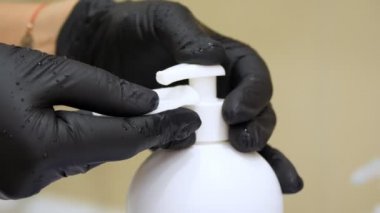 Yakın plan, siyah tıbbi eldivenli eller kozmetik ürünü, tonik, pamuk bloknotları sıkıyor. Tıp, kozmetoloji. Antiseptik maddeler..