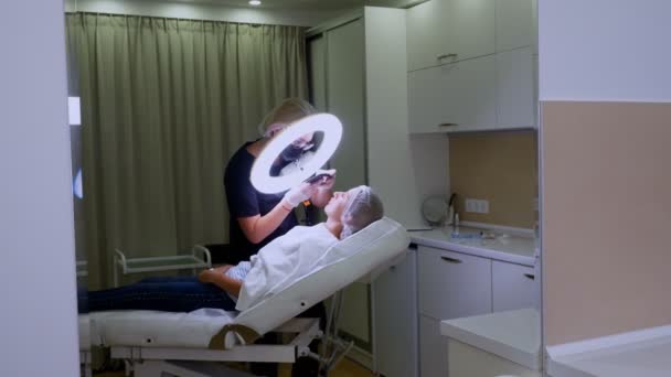 Female Doctor fotografa il risultato del suo lavoro su un telefono cellulare. procedura di aumento del labbro con iniezioni di acido ialuronico — Video Stock