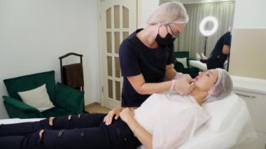 Doktor, dudak büyütme ameliyatından sonra hastaya hyaluronik asit enjeksiyonları hakkında danışır..