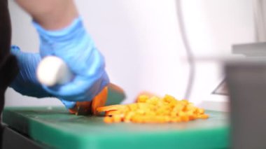 Yakın plan, koruyucu eldivenli şef, kesme tahtasındaki havucu kesiyor. Yemek, yemek, kantin, yemek servisi. Sağlık, güvenlik ve yeniden açılış kavramı