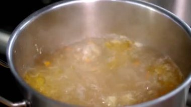 Yemek pişirmek. Yakın plan. Et suyu tencerede kaynıyor, buhar geliyor. Sağlıklı gıda ve güvenlik kavramı. Matarayı yeniden aç