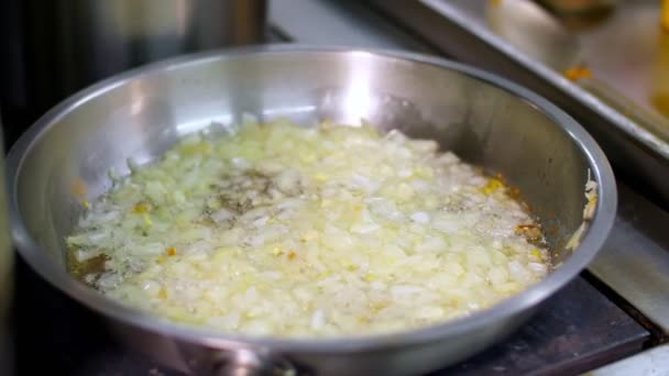 Cooking. close-up, fried onions in frying pan. the cook, in protective gloves, stirs the onion and add the diced carrots. health food and safety concept. reopening canteen — Stock Video
