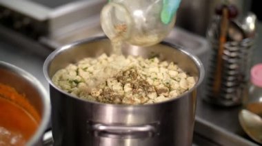 Yemek pişirmek. Yakın plan. Şef, koruyucu eldivenlerle çorbaya baharat koyar ve tencereyle büyük kaşıkla karıştırır. Sağlıklı yemek. Güvenlik kavramı. Matarayı yeniden açıyorum. Gönüllülük ve yardım