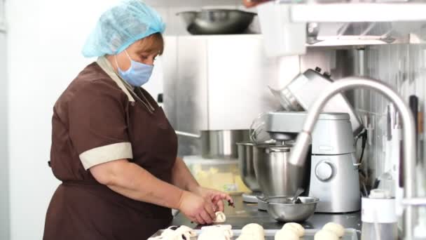 Cocinar. panadería. panadero mujer, en máscara protectora, hace pasteles, bollos con semillas de amapola. comida saludable. voluntariado y caridad. comedor de reapertura. concepto de seguridad. — Vídeo de stock