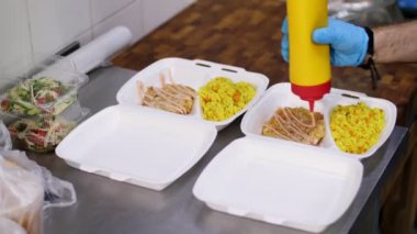 Yemek pişirmek. Yakın plan Gönüllü, koruyucu eldivenler giyip fakir insanlara ulaştırılmak üzere beslenme çantalarına bedava sıcak yemek koyun. Yemek servisi. Yardım projesi, bağış yardımı,