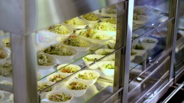 Koken. close-up. Keuken cafetaria buffet met eten, veel kommen salades. Self-service food display vitrine. Gezondheidsvoedsel. vrijwilligerswerk en liefdadigheid. Heropenen. veiligheidsconcept. — Stockvideo