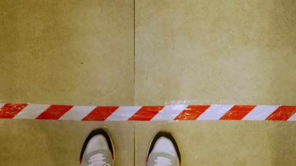 Närbild. manliga ben i sneakers korsar speciella linjer på golvet, vilket innebär att hålla avståndet mellan besökarna. Nya restriktiva åtgärder enligt covid-19, — Stockvideo