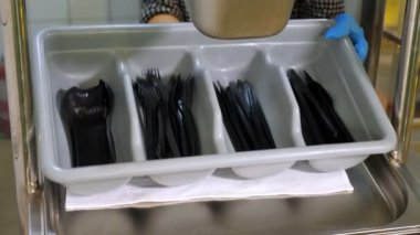 Yakın plan. Garson, koruyucu eldivenlerle, tek kullanımlık çatal bıçak seti ile bir tepsi koyar, self-servis kafeteryasına ya da açık büfe restoranına. Sağlıklı yemek. Gönüllü olmak ve yardım. Yeniden açılıyor. güvenlik kavramı