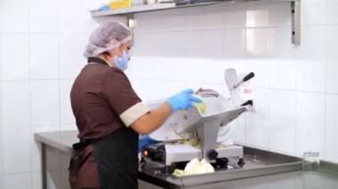Yemek pişirmek. Mutfak işçisi, koruyucu eldivenler ve maske takmış, elektrikli öğütücüde taze lahana kesiyor. Sağlıklı yemek. Covid-19 'dan sonra tekrar açılıyor. Güvenlik kavramı. Gönüllülük ve yardım.