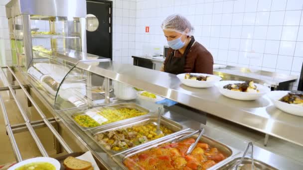 Waitress, in protective gloves and mask, puts food on plates and serves to customers in self-service cafeteria or buffet restaurant. reopening after covid-19. safety concept. health food. — Stock Video