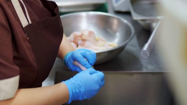 Nahaufnahme. Küchenhilfe wäscht in Schutzhandschuhen rohe Hühnerkeulen vor dem Kochen. gesunde Ernährung. Freiwilligenarbeit und Wohltätigkeit. Wiedereröffnung nach Covid-19. Sicherheitskonzept.