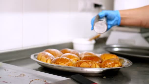 Cocinar. panadería. Primer plano. panadero, en guantes de protección, espolvorea azúcar en polvo sobre pasteles recién horneados. comida saludable. reapertura después de covid-19. concepto de seguridad. voluntariado y caridad. — Vídeos de Stock