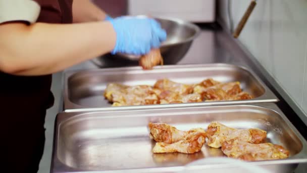 Gros plan. Travailleur de la cuisine, dans des gants de protection, pose les jambes de poulet crues dans la plaque de cuisson pour la cuisson au four. nourriture santé. bénévolat et charité. réouverture après covid-19. concept de sécurité. — Video