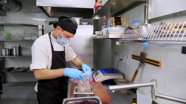 Chef, in beschermende handschoenen en masker, kookt in de keuken. Gezondheidsvoedsel. heropenen na Covid-19. veiligheidsconcept. vrijwilligerswerk en liefdadigheid — Stockvideo