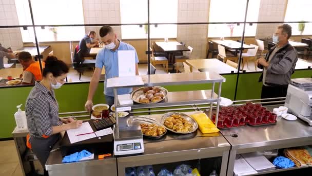 CHERKASSY, UKRAINE, 14 sierpnia 2020: mężczyzna w masce ochronnej jada lunch i płaci gotówką w samoobsługowej kawiarni lub restauracji bufetowej. ponowne otwarcie po covid-19. koncepcja bezpieczeństwa. żywność dla zdrowia — Wideo stockowe