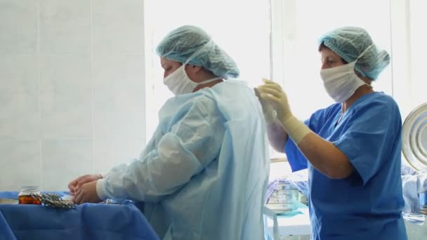 A nővér felvesz egy speciális egyenruhát, védőruhát. felkészülés a műtétre. Gyógyszer, kórház, műtét. Újraélesztés. covid-19 világjárvány — Stock videók