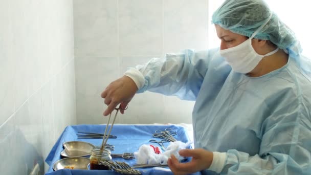 Медсестра в медичній масці зволожує шматочки вати в розчині йоду. підготовка до операції. медицина, лікарня, операція. реанімація. пандемія ковадла-19 — стокове відео