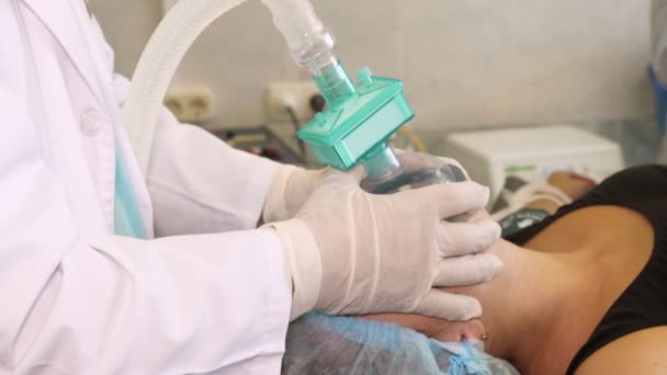 Close-up. The anesthesiologist, in medical gloves, prepares female patient for surgery, regulates the oxygen mask. medicine. surgery and resuscitation in hospital. covid-19 pandemic — Stock Video