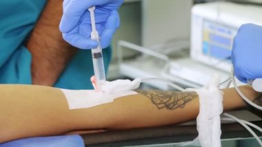 Yakın çekim, periferik venöz kateter hastanın koluna takılır. Doktor ya da hemşire, tıbbi eldivenlerle, şırıngayı kateterden enjekte ediyor. Ameliyat. anestezi.