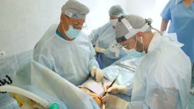 Cerrah, kadın hastaya lazer kullanarak göğüs altından bir kesik atar. Ona başka bir doktor yardım ediyor. Göğüs büyütme estetiği. Mammaplasti. Göğüs kanseri
