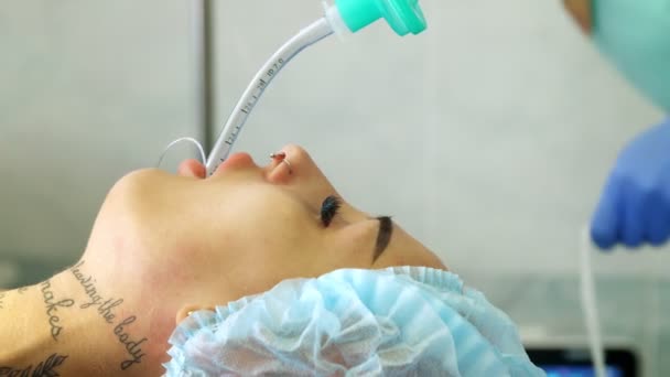 Primer plano. una enfermera, con guantes médicos, fija un tubo de la máquina de anestesia a la garganta de los pacientes. anestesia. preparación para la cirugía. — Vídeos de Stock