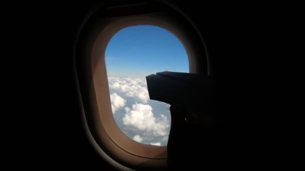 Gros plan. silhouette sombre de main d'enfant avec jouet. Le gamin est assis près de la fenêtre de l'avion et joue avec un jouet en papier sur le fond de la fenêtre de l'avion, illuminateur . — Video