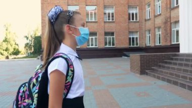 Dijital medikal elektronik termometre kullanan bayan güvenlik görevlisi okul binasına girmeden önce kızın vücut ısısını ölçüyor. Covid19 'dan sonra okula döndüm.