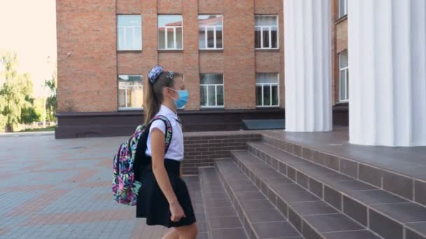 La guardia de seguridad femenina, utilizando termómetro electrónico médico digital, mide, comprueba la temperatura corporal de la colegiala antes de permitirle entrar en el edificio de la escuela. Volver a la escuela después de covid19 — Vídeos de Stock