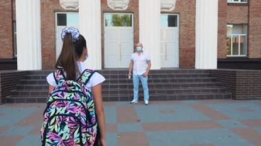 Güvenlik görevlisi, dijital medikal elektronik termometre kullanarak okul binasına girmeden önce kızın vücut ısısını ölçüyor. Covid19 salgınından sonra okula döndüm.
