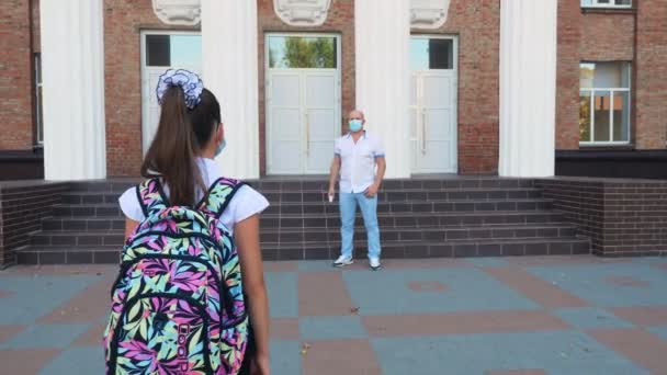 Security guard, using digital medical electronic thermometer, screens body temperature of schoolgirl before allowed her to go into school building. Back to school after covid19 outbreak — Stock Video