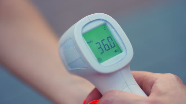 Close-up. digitale infrarood-contactloze thermometer voor het screenen van de lichaamstemperatuur. Het is 36,3 graden Celsius. Terug naar school na de uitbraak van de covid19. — Stockvideo