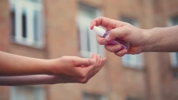 Närbild. man hand håller liten spray antiseptisk dispenser och sprutar den på barnens händer, på skolan byggnad bakgrund. Tillbaka till skolan efter 19 utbrott. — Stockvideo