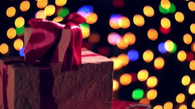 Pembe kurdeleli güzel paketlenmiş hediyeler. Bokeh ışıkları ya da parlak çelenkler hakkında sunumlar. Yakın çekim, rotasyon. Noel ya da yeni yıl. Yardım konsepti. Şenlikli atmosfer.