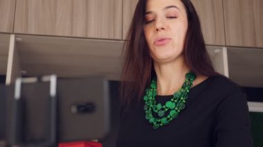 Tasarımcı hediye paketliyor. Çekici kadın dekoratör online yayın, konferans, video blogu, web sitesi, akıllı telefonun önünde duruyor. çevrimiçi çalış.