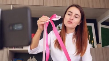 Tasarımcı hediye paketliyor. Çekici kadın dekoratör çevrimiçi eğitim veriyor, video konferansı yapıyor video blogunu kaydediyor, Webinar giyiyor, akıllı telefonun önünde duruyor. çevrimiçi çalış.