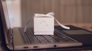 Hediyeler yakın çekimde paketleniyor. Dizüstü bilgisayarda küçük bir kutu. Laptop klavyesinde fiyonklu hediye kutusu var. İnternet alışveriş konsepti. çevrimiçi satış