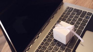 Hediyeler yakın çekimde paketleniyor. Dizüstü bilgisayarda küçük bir kutu. Laptop klavyesinde fiyonklu hediye kutusu var. İnternet alışveriş konsepti. çevrimiçi satış