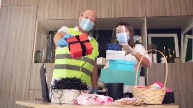 Paketler için teslimat hizmeti, hediyeler. Kurye koruyucu maske takıyor. Tasarımcı, maskeli, hediye çantası takıyor. Koronavirüs salgını yüzünden eve servis. Online satış, online alışveriş.