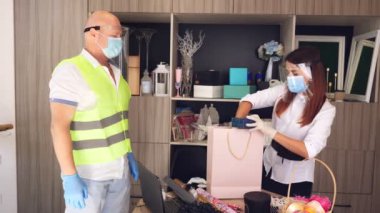 Paketler için teslimat hizmeti, hediyeler. Kurye koruyucu maske takıyor. Tasarımcı, maskeli, hediye çantası takıyor. Koronavirüs salgını yüzünden eve servis. Online satış, online alışveriş.