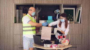 Paketler için teslimat hizmeti, hediyeler. Kurye koruyucu maske takıyor. Tasarımcı, maskeli, hediye çantası takıyor. Koronavirüs salgını yüzünden eve servis. Online satış, online alışveriş.