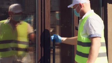 Paketler için teslimat hizmeti, hediyeler. Kurye koruyucu maske takıyor. Tasarımcı, maskeli, ona hediye paketi veriyor. Koronavirüs salgını yüzünden eve servis. çevrimiçi satış.