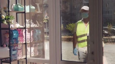 Paketler için teslimat hizmeti, hediyeler. Kurye koruyucu maske takıyor. Tasarımcı, maskeli, ona hediye paketi veriyor. Koronavirüs salgını yüzünden eve servis. çevrimiçi satış.