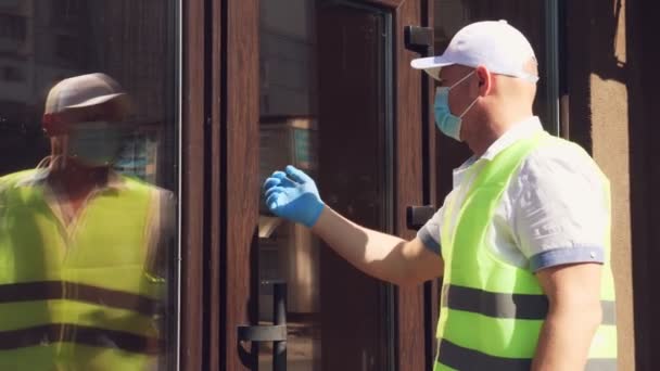 Servizio di consegna per pacchi, regali. Il corriere indossa una maschera protettiva. designer, in maschera, gli dà una borsa regalo. consegna a domicilio dovuta a pandemia di coronavirus. vendite online. — Video Stock